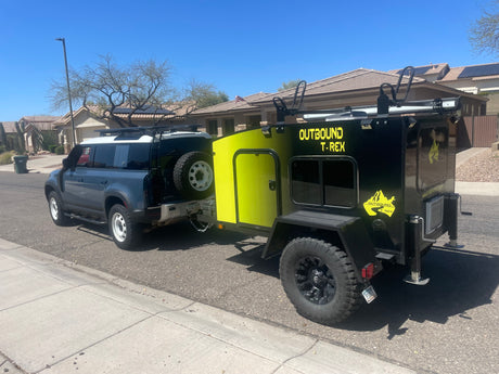 Adventure-ready RV rental: Land Rover Defender towing a unique Outbound T-Rex off-road camper.