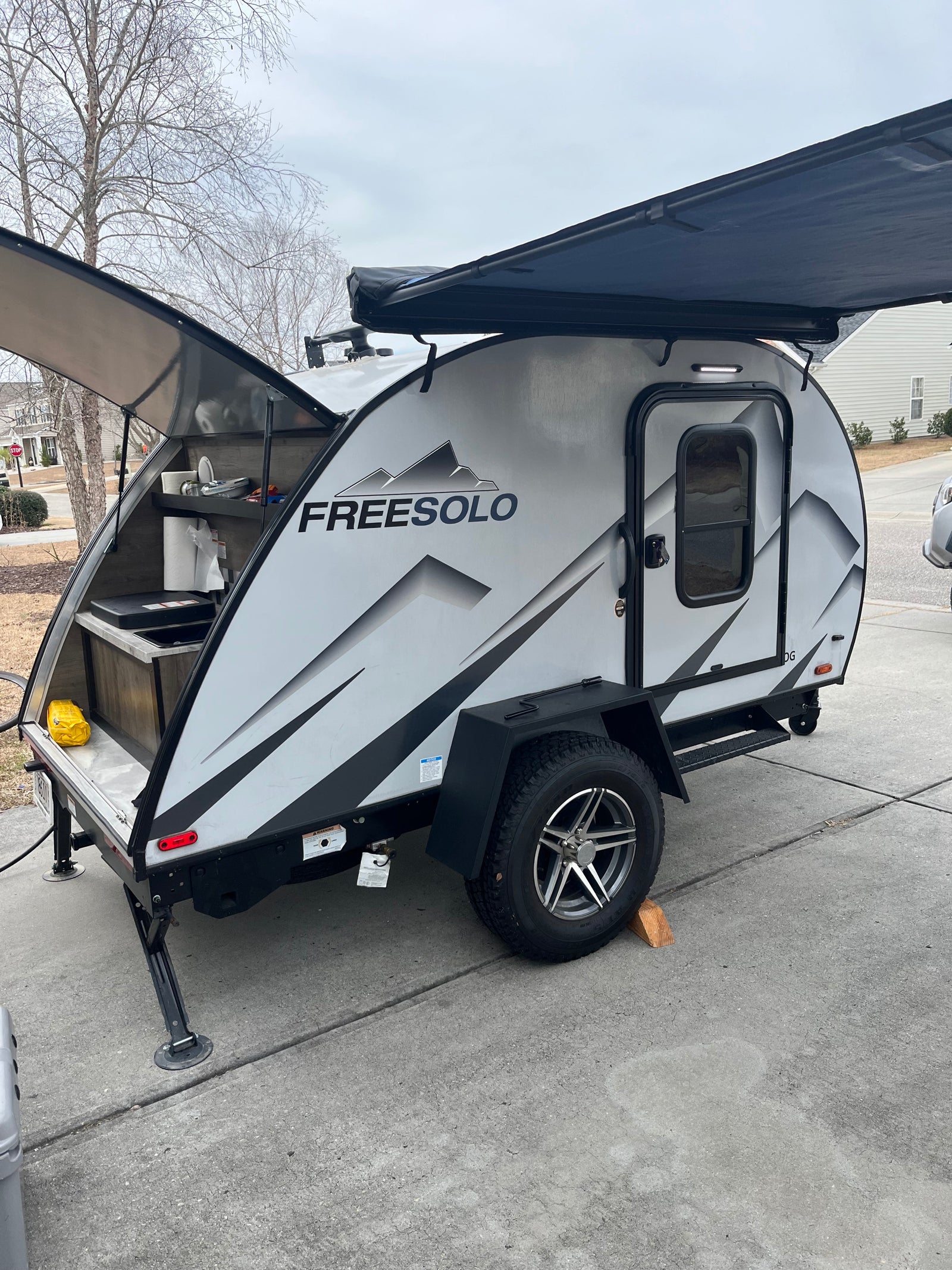 A sleek grey FREESOLO teardrop camper RV rental with an open rear galley kitchen and extended awning. Ready for adventure.