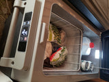 Open portable fridge/freezer, perfect for an RV rental, stocked with sweet peas, frozen food, drinks & water for cool travel storage.