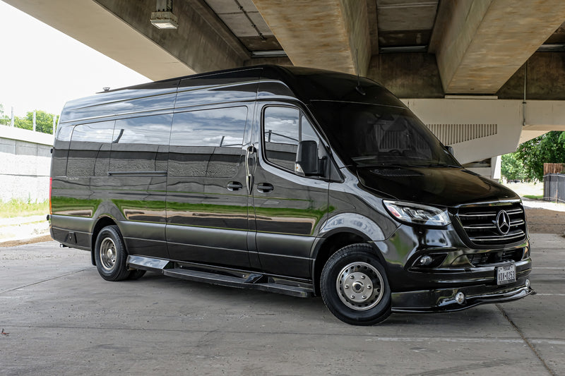 This polished black Mercedes-Benz Sprinter van is ready for your next rv rental adventure, parked beneath a concrete bridge. — photo 12