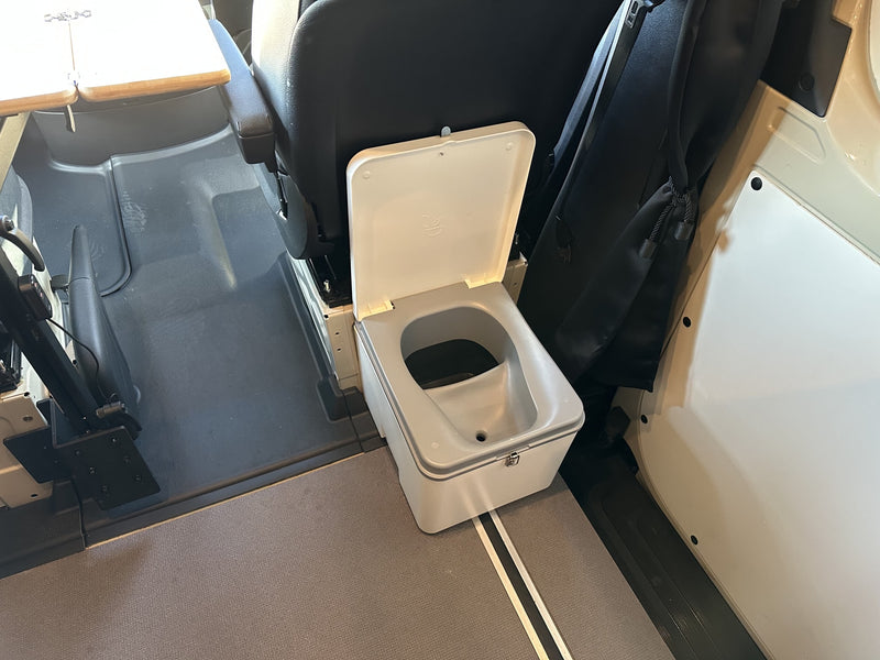  showcasing the rugged Kumho Road Venture AT tire and side step of a cream-colored van.|Spacious RV rental: front cabin with swiveled black seats — photo 14