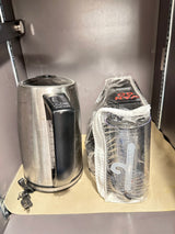 RV rental kitchen: stainless steel electric kettle and a new, wrapped "VAN GO" appliance, likely a coffee maker, on a mat.