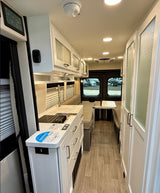 RV rental interior: Modern kitchenette, comfy seating, and smart storage define this compact camper van living space.