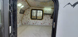 Explore this cozy RV rental interior: comfortable bed, unique bird & birch wall decor, map ceiling, and bright lighting.