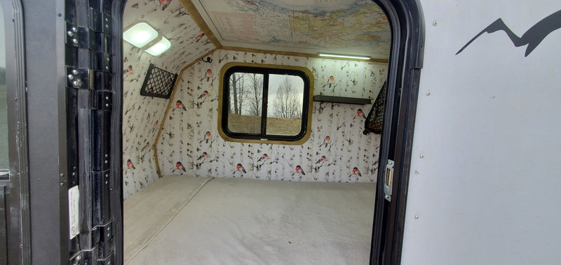 Explore this cozy RV rental interior: comfortable bed, unique bird & birch wall decor, map ceiling, and bright lighting. — photo 7