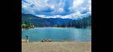 Beautiful blue mountain lake with pine forests, ideal for an RV rental getaway. Features a rocky shore & docks for recreation.