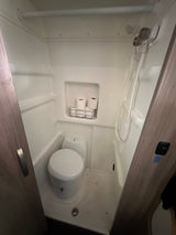 This compact wet bath in an RV rental features a toilet, shower, and convenient toilet paper storage.