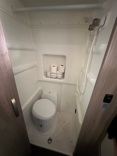 This compact wet bath in an RV rental features a toilet, shower, and convenient toilet paper storage.