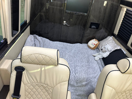 Luxurious RV rental interior: Cream seats, cozy bed with stuffed animals. Perfect for comfortable travel.