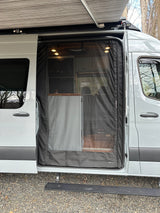 A light grey rv rental van, with its side door open, featuring a mesh screen and extended awning.