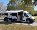 White Ram ProMaster rv rental conversion van, solar panels, awning, outdoor seating, and a dog at camp.