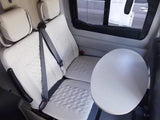 Bright, modern RV rental interior: white quilted seats and a round table for comfort on the road.