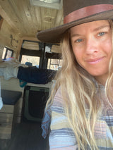 Smiling woman in her cozy RV rental, showcasing the custom wood-paneled interior. Ideal for mobile living.