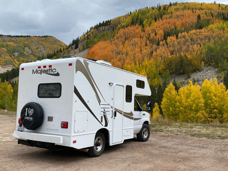 Majestic RV rental parked amidst stunning fall colors and mountains, ready for camping.