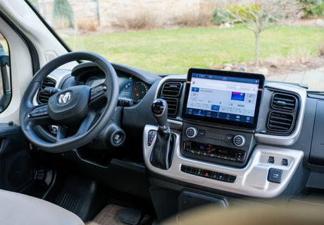 Spacious RV rental cabin with large infotainment screen, RAM steering wheel, and modern climate controls for comfortable travel.