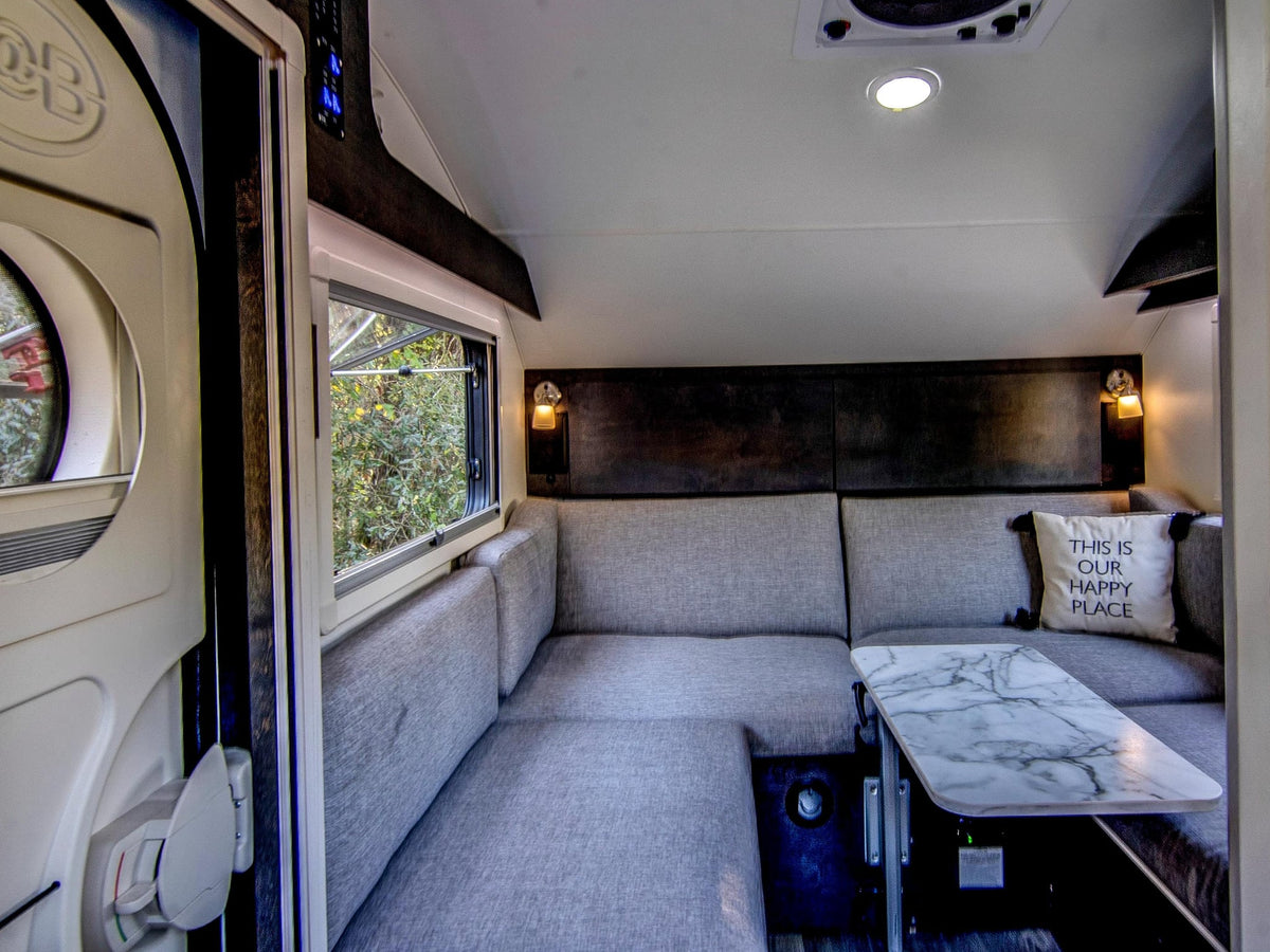  parked on grass with lush trees and Spanish moss in the background.|Dark teardrop **rv rental** with open side hatches — photo 9