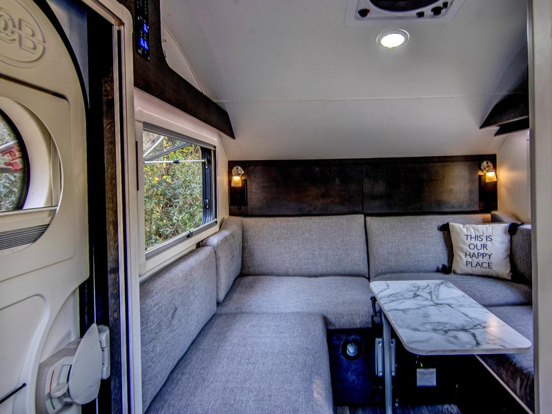  parked on grass with lush trees and Spanish moss in the background.|Dark teardrop **rv rental** with open side hatches — photo 9