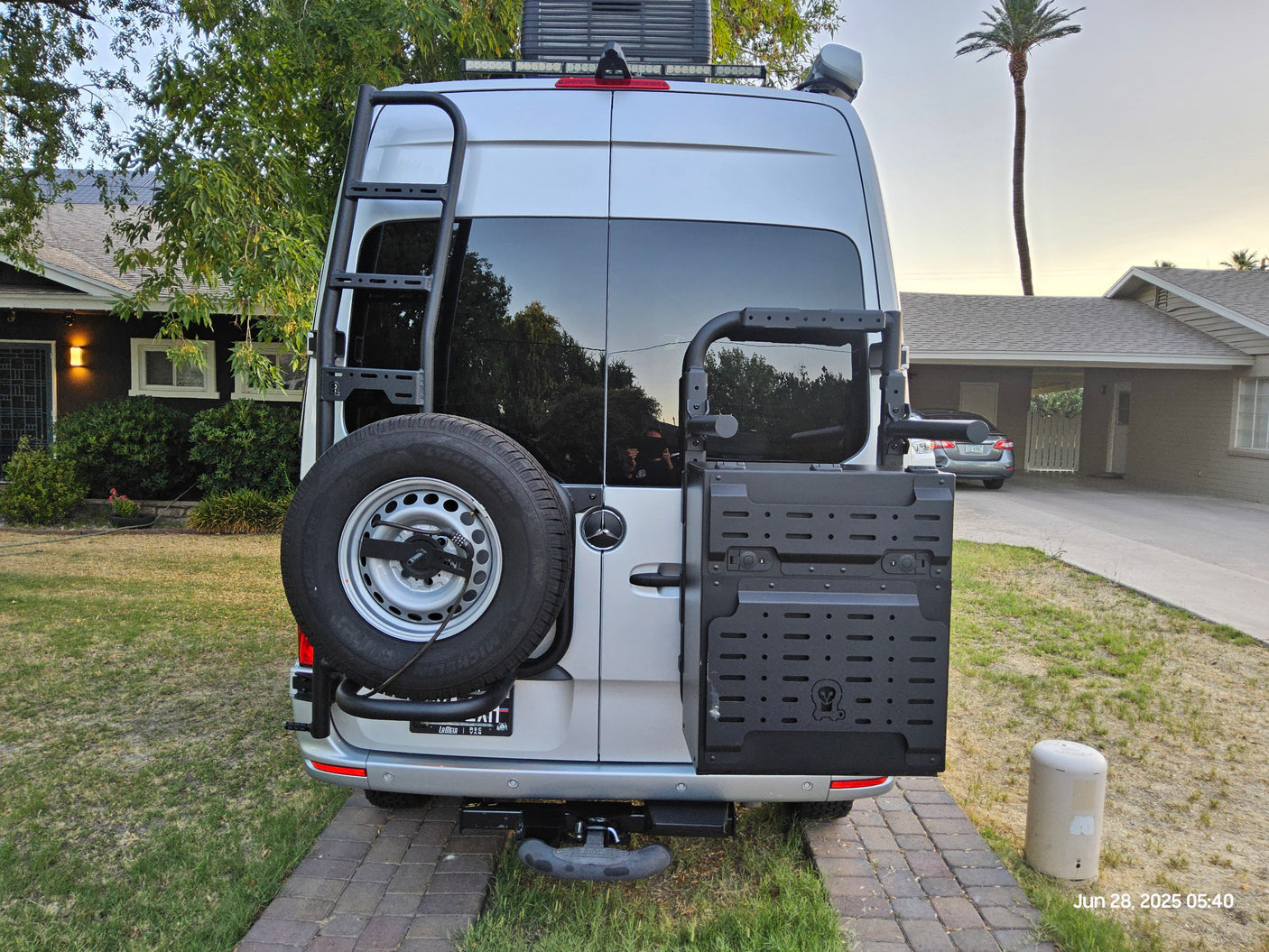 Silver Sprinter van, a custom rv rental, with rear ladder, spare tire, and gear storage for your next trip.
