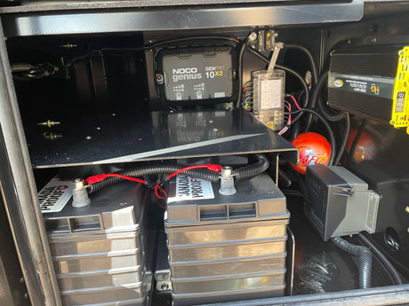 RV rental's power hub: deep-cycle batteries, NOCO charger, Go Power inverter, and fuse panel for off-grid adventures.