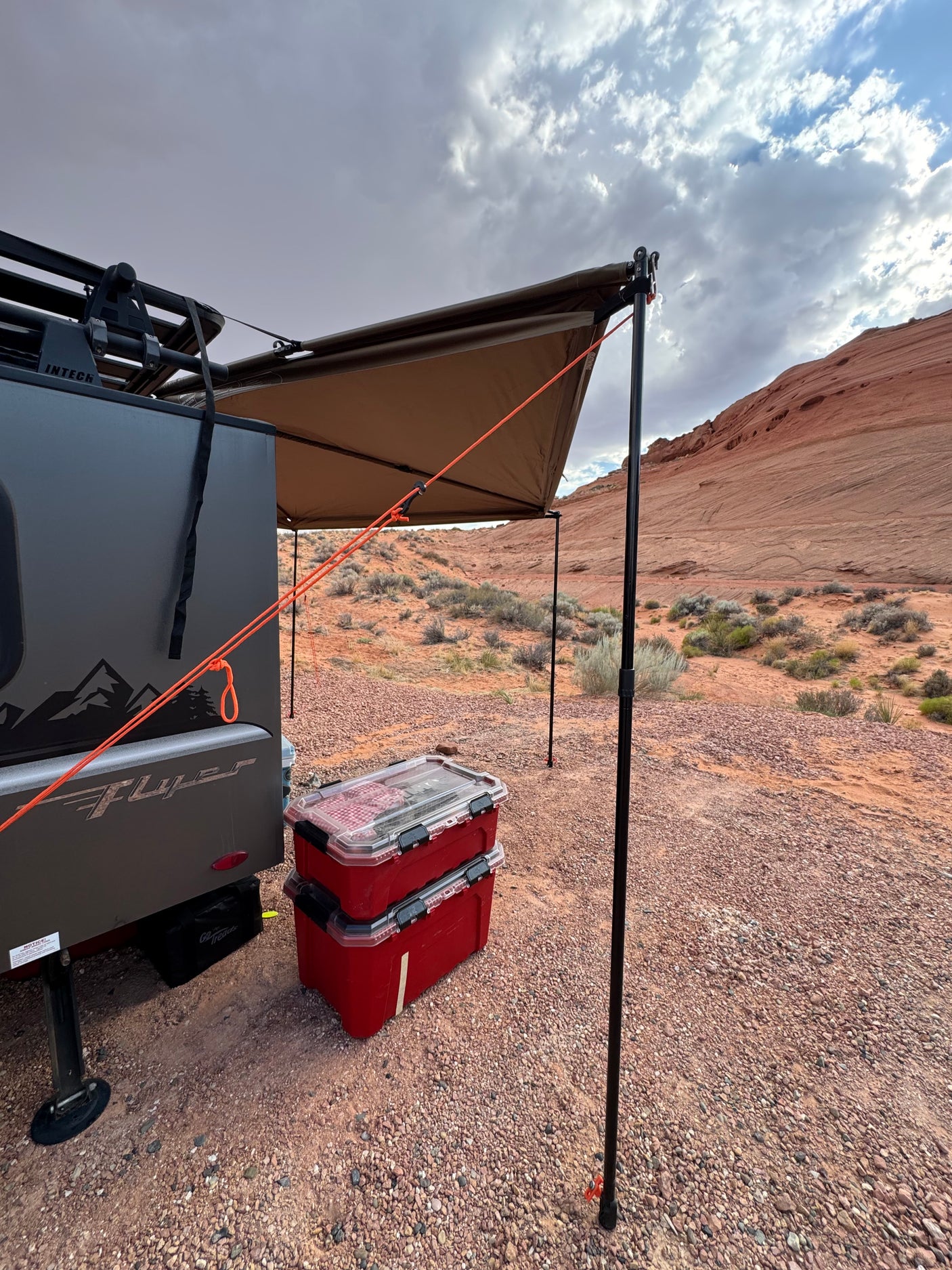 Enjoying the desert view from an RV rental with an extended awning. A Flyer camper parked at a rugged campsite.