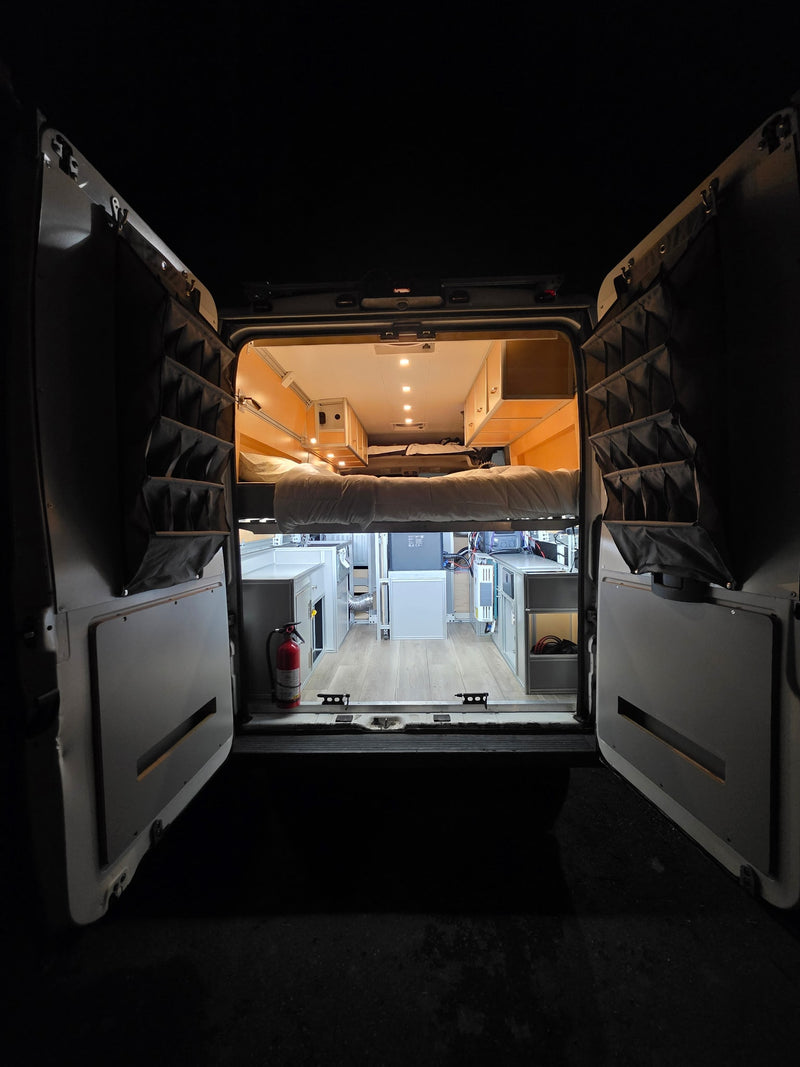 Step into this bright rv rental camper van, revealing a raised bed, cabinetry, and door organizers, perfect for mobile adventures. — photo 9