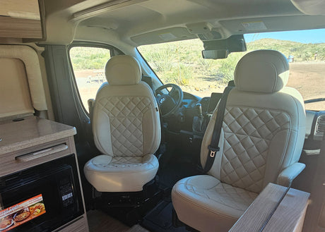 Experience comfort in this RV rental's interior, showcasing cream quilted seats, an equipped kitchenette, and desert views.