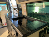 Inside an RV rental: sleek kitchen with sink & cooktop, offering a brilliant water view from the large window.
