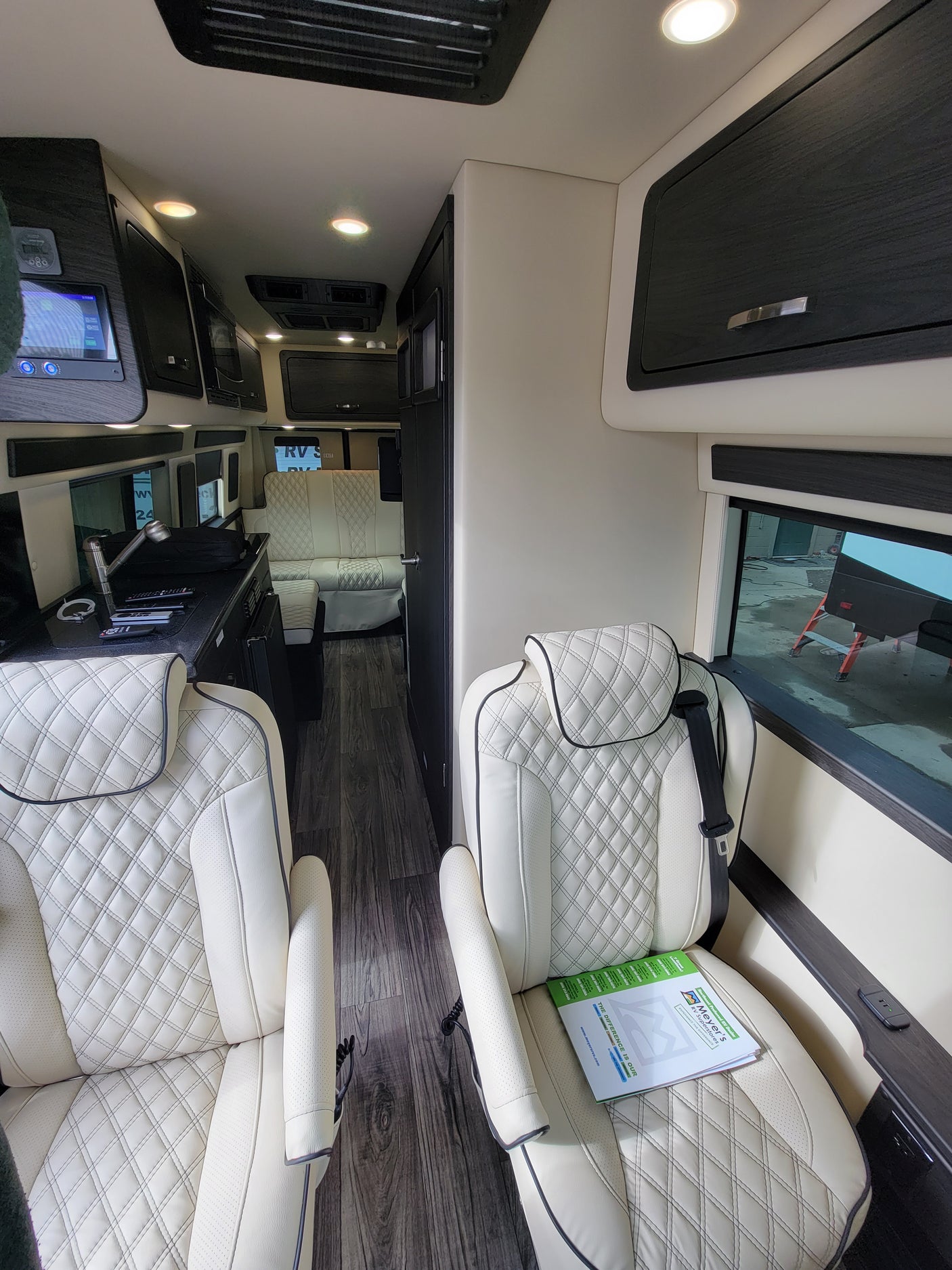 Step inside this plush RV rental featuring cream quilted leather seats, dark wood trim, and a modern control panel.