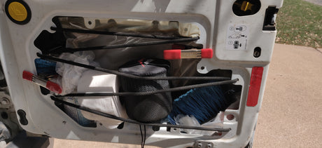 Inside an RV rental's rear door: Bungee cord netting neatly holds camping gear, toilet paper, and cleaning supplies.