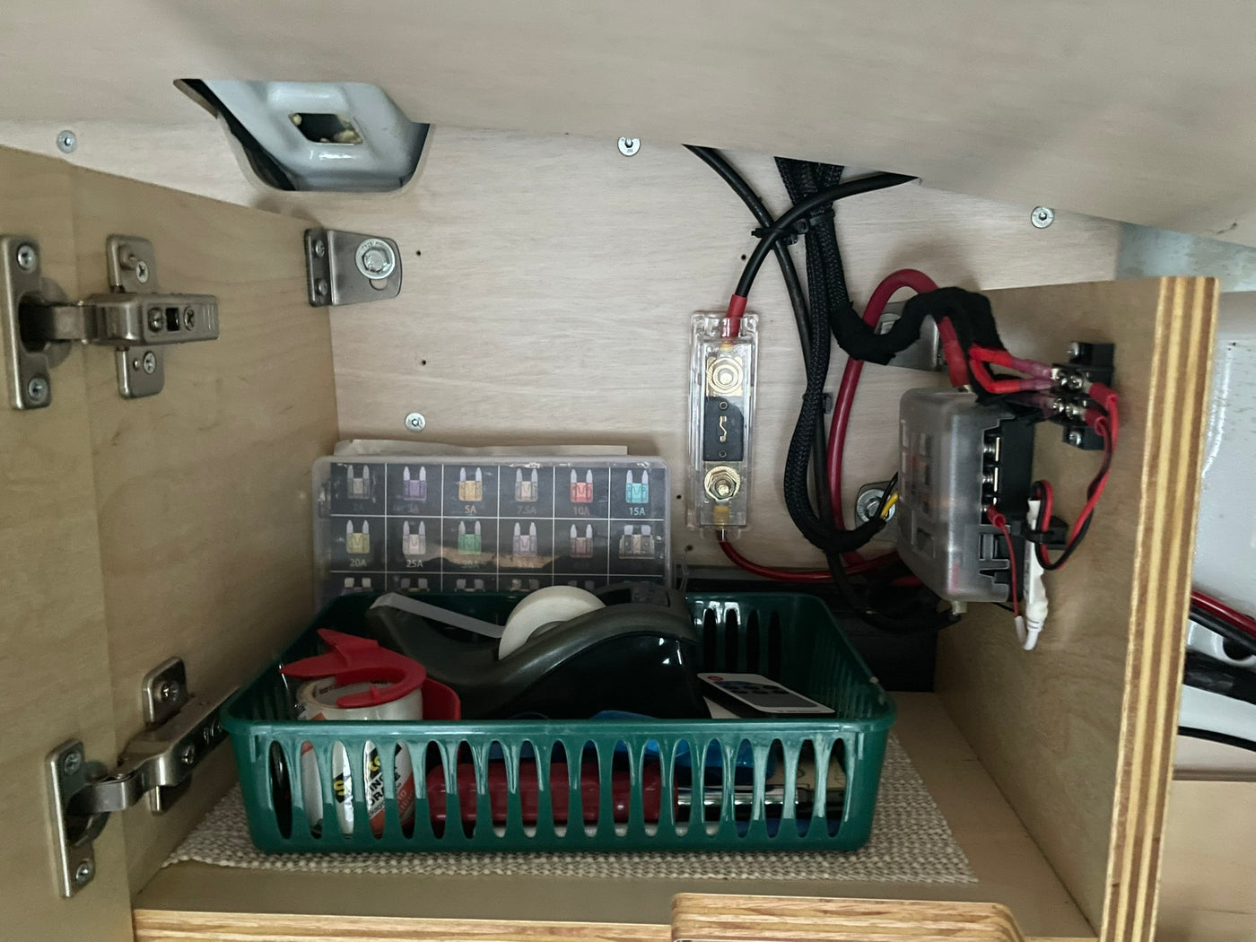 RV rental utility space: a fuse box, thick wiring, and a storage basket for essentials, all neatly fitted in a wood cabinet. — photo 9