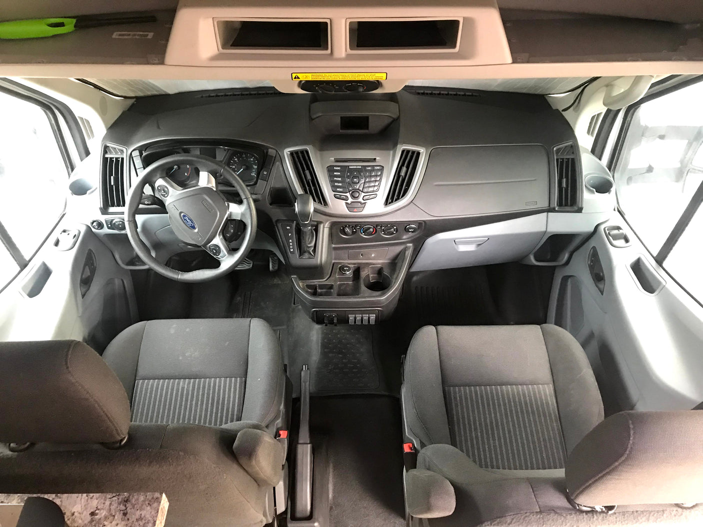 RV rental van's spacious front cabin, showing dashboard, steering wheel, front seats, and overhead storage.