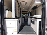 RV rental interior: Aisle view revealing flexible sleeping with a fold-up bunk, a fixed bed, and ample storage.