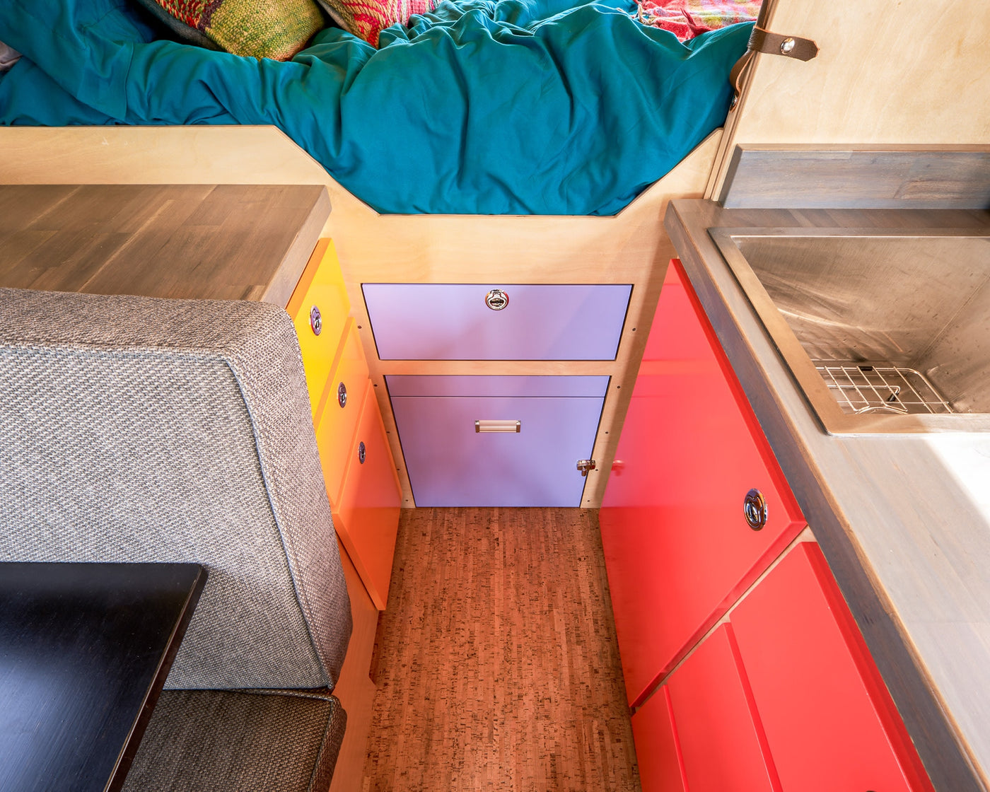 Colorful RV rental interior: cozy bed, compact kitchen with sink, bright storage cabinets, and comfortable seating. — photo 16