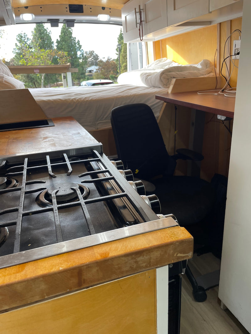  & bed. Ideal for your next rv rental.|A gray Ford E-Transit van is parked in an autumn lot. Its spacious interior makes it a potential candidate for an rv rental conversion.|RV rental: Enjoy van life in this cozy camper with a comfy bed — photo 9