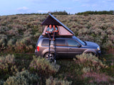 Happy couple enjoys rooftop tent camping on their SUV, a compact alternative to an RV rental for a nature escape.