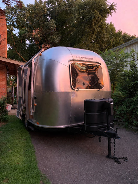 Shiny Airstream rv rental glows pink with sunset reflections