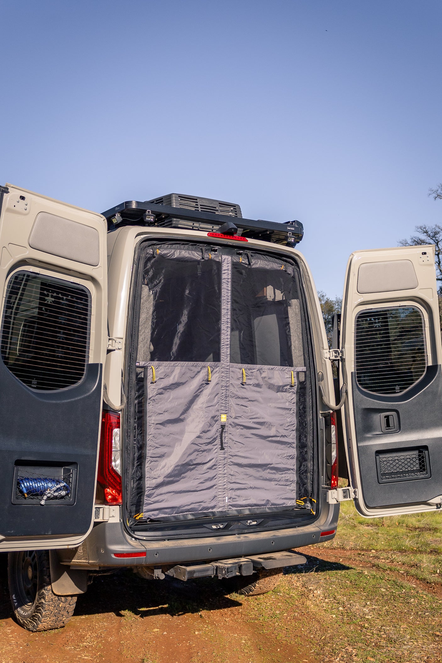 This RV rental camper van features open rear doors with a privacy bug screen, ready for outdoor adventure.