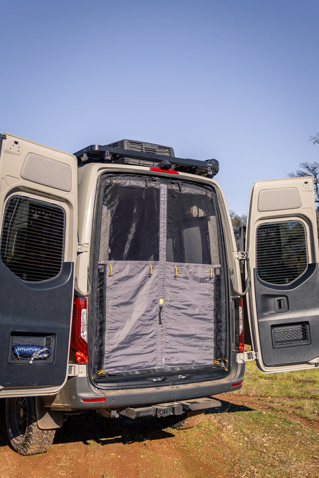 This RV rental camper van features open rear doors with a privacy bug screen, ready for outdoor adventure.