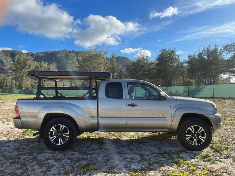 Silver Toyota Tacoma with a bed rack & rooftop tent, parked on sandy ground. Great for camping, offering RV rental-like freedom near mountains. — photo 15