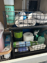RV rental: Essential cleaning supplies like Mrs. Meyer's soap, scrub brush, and towels in organized cabinet storage.