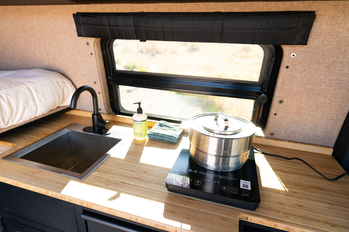 Cozy rv rental kitchenette: sink, induction cooktop, and window view, perfect for van life cooking & camping adventures. — photo 17