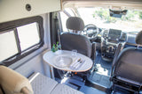 Inside an RV rental, showing a dining area with a set table, swiveled passenger seat, and front cabin.