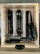 Organized RV rental kitchen storage unit with clear bins holding black cutlery and knives. Space-saving.
