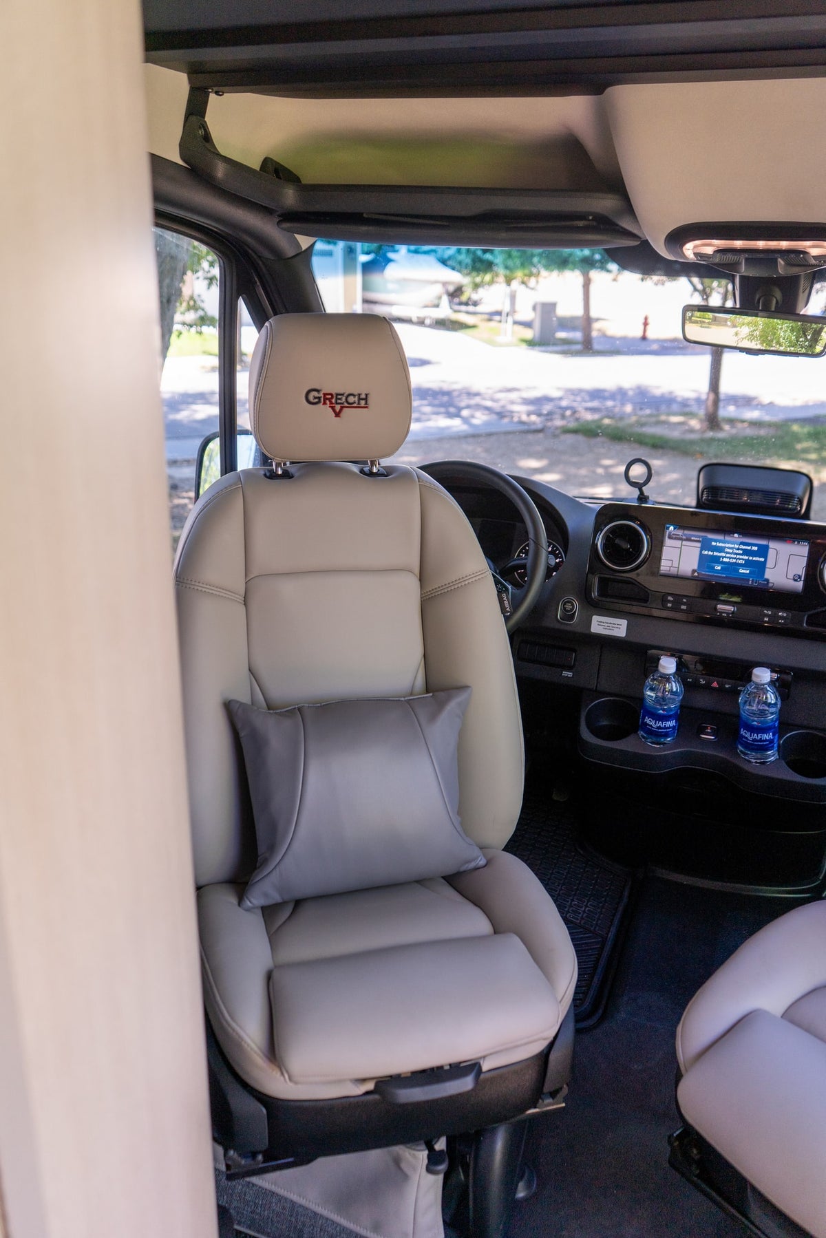 Grech RV rental's spacious front cabin: premium light-colored passenger seat, grey pillow, dashboard, & infotainment. — photo 11