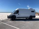 White Ram ProMaster camper van by a sunny white sand beach. Ideal for an RV rental beach adventure.