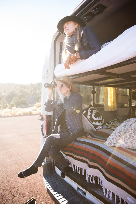 RV rental adventure: Two women in their camper van, one on the upper bunk, one with binoculars below.