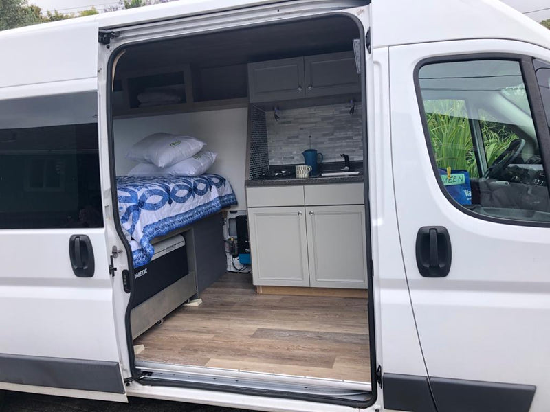  and striking gray/black tile backsplash. Perfect for on-the-go cooking.|Cozy RV rental interior: A person relaxes on a bed — photo 7