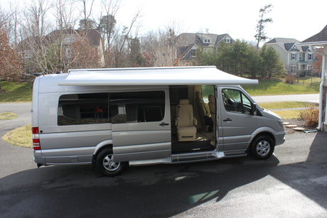 Silver Mercedes Sprinter luxury RV, ideal for rv rental adventures. Awning extended, side door open showing plush interior.