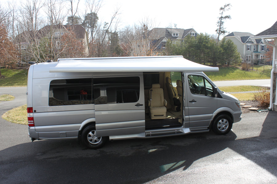 Silver Mercedes Sprinter luxury RV, ideal for rv rental adventures. Awning extended, side door open showing plush interior.