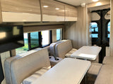 Modern RV rental interior: spacious dinette, comfortable seating, and scenic water views.